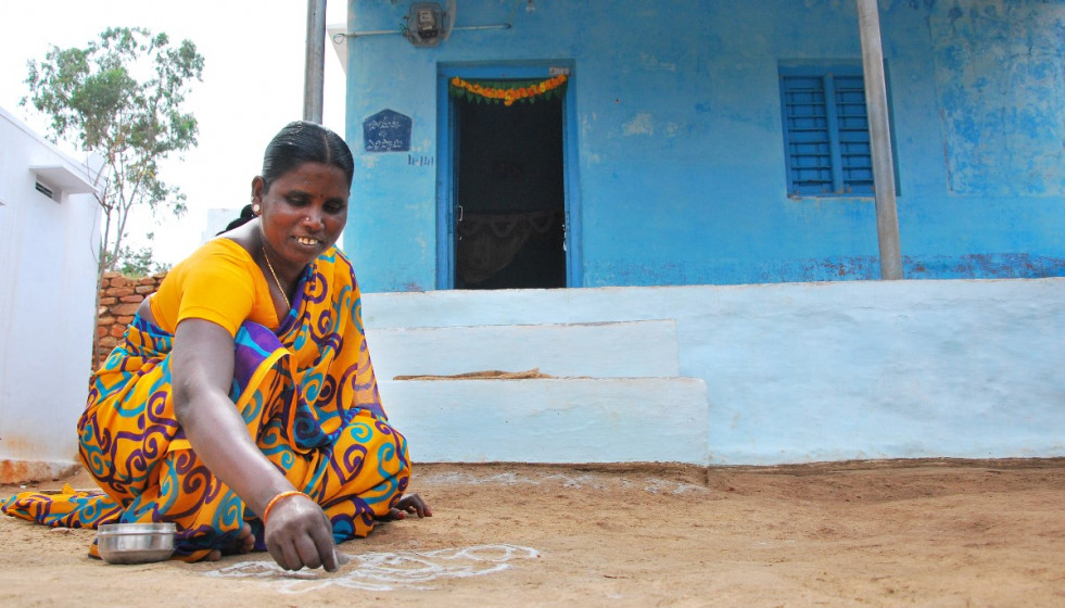 Una mujer india ante su vivienda