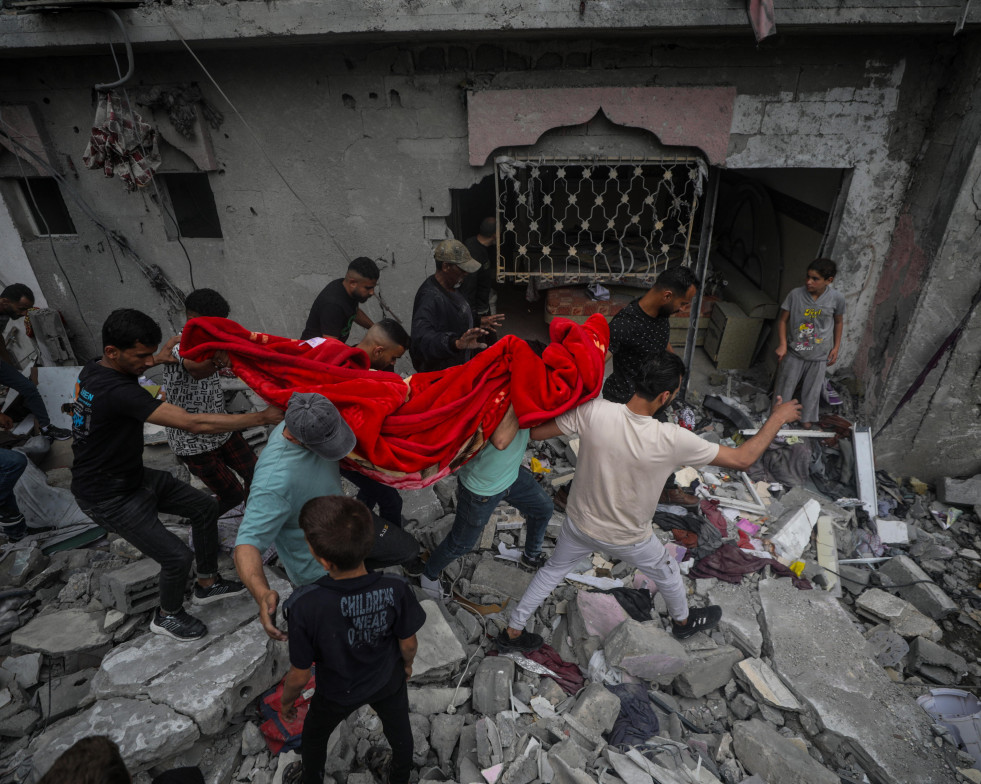 Palestinos recuperan los restos de una mujer entre los escombros de una casa destruida tras un ataque aéreo israelí en el campo de refugiados de Al Nusairat