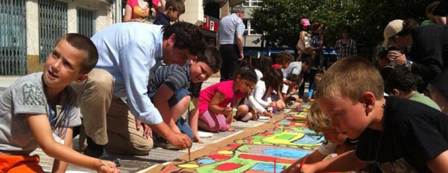 Los niños elaboran en la calle el cartel modernista gigante de cara a la feria