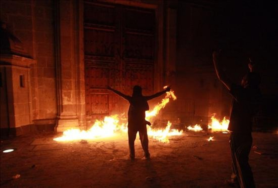 Un grupo de encapuchados incendia la puerta del Palacio Nacional al finalizar la marcha por los 43 jóvenes asesinados