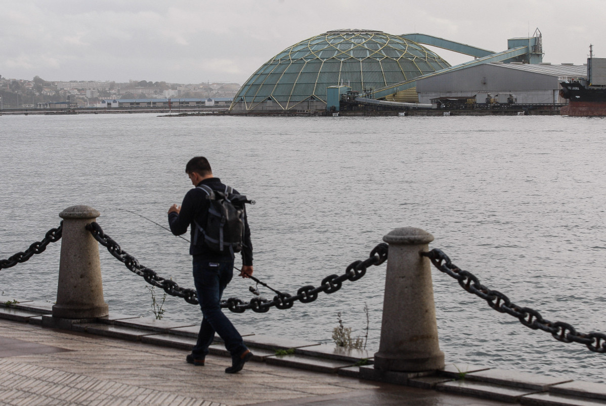 Un hombre camina por el paseo de O Parrote, frente a la Medusa situada en el muelle del Centenario  quintana