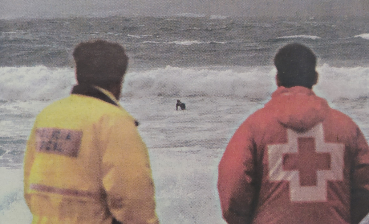 Un policu00eda local y un miembro de la Cruz Roja advierten del peligro a un surfista en el Orzu00e1n