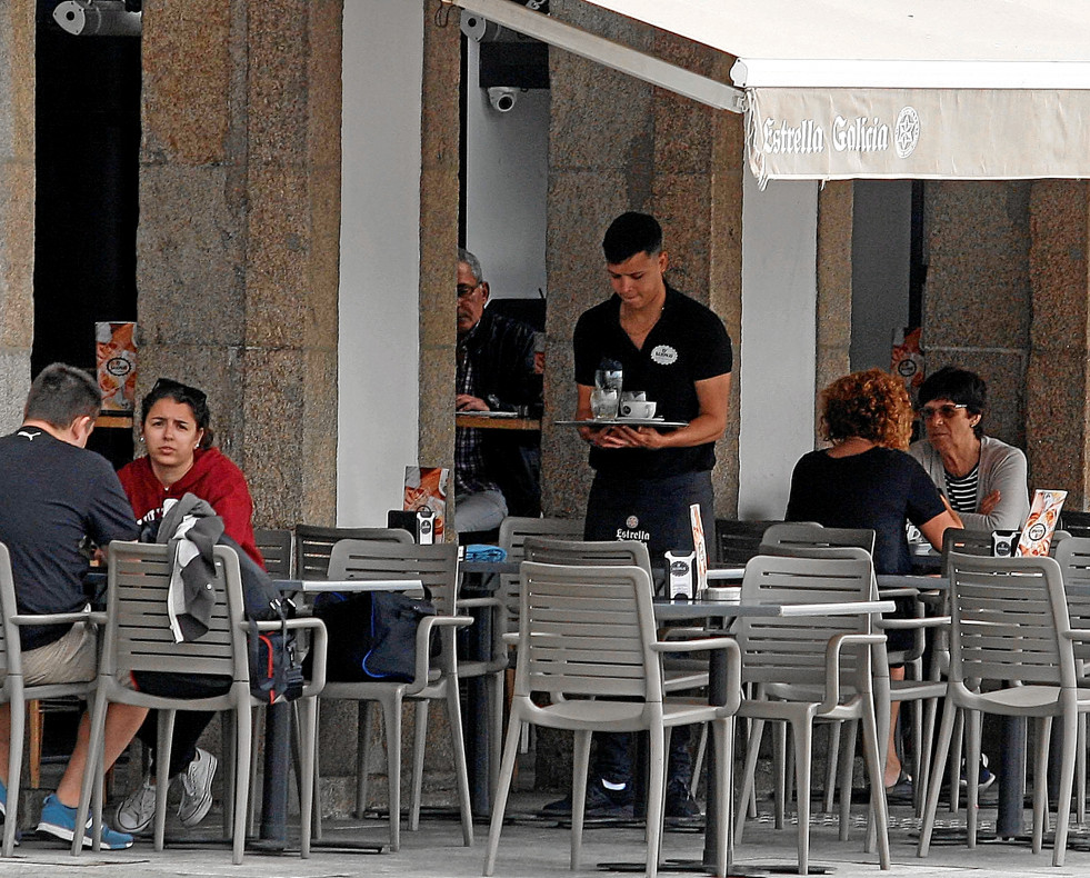 Un camarero atiende una terraza en un local de hostelería coruñés  AEC
