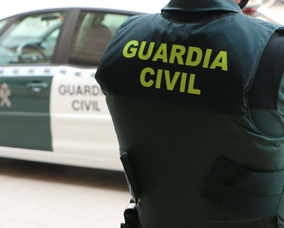 Archivo - Un agente de la Guardia Civil, de espaldas, junto a un vehículo oficial. Imagen de archivo