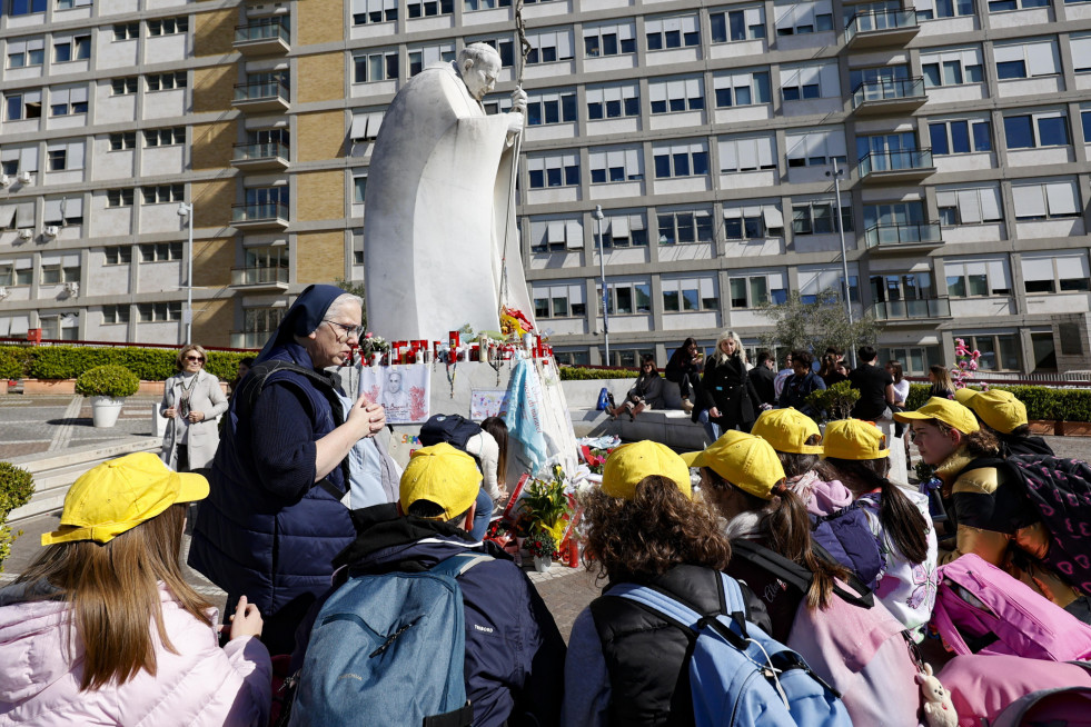 ROME (Italy), 18/03/2025.- Children from a primary school in Rivoli, near Turin, pray in front of the statue of John Paul II at the entrance to the Gemelli Hospital, where Pope Francis is hospitalized