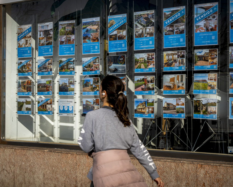 SANTANDER (ESPAÑA), 20/02/2025.- Una mujer pasa junto a una inmobiliaria en Santander este jueves cuando se ha conocido que en 2024 se compraron 641.919 viviendas en toda España al calor de la bajad