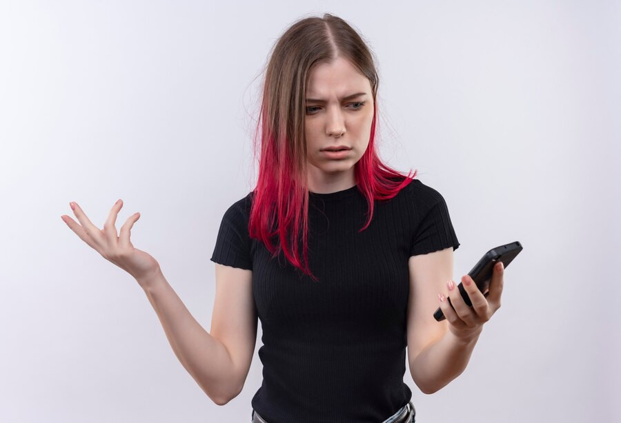 Confundida joven hermosa mujer vestida camiseta negra mirando telefono su mano pared blanca aislada 141793 35628