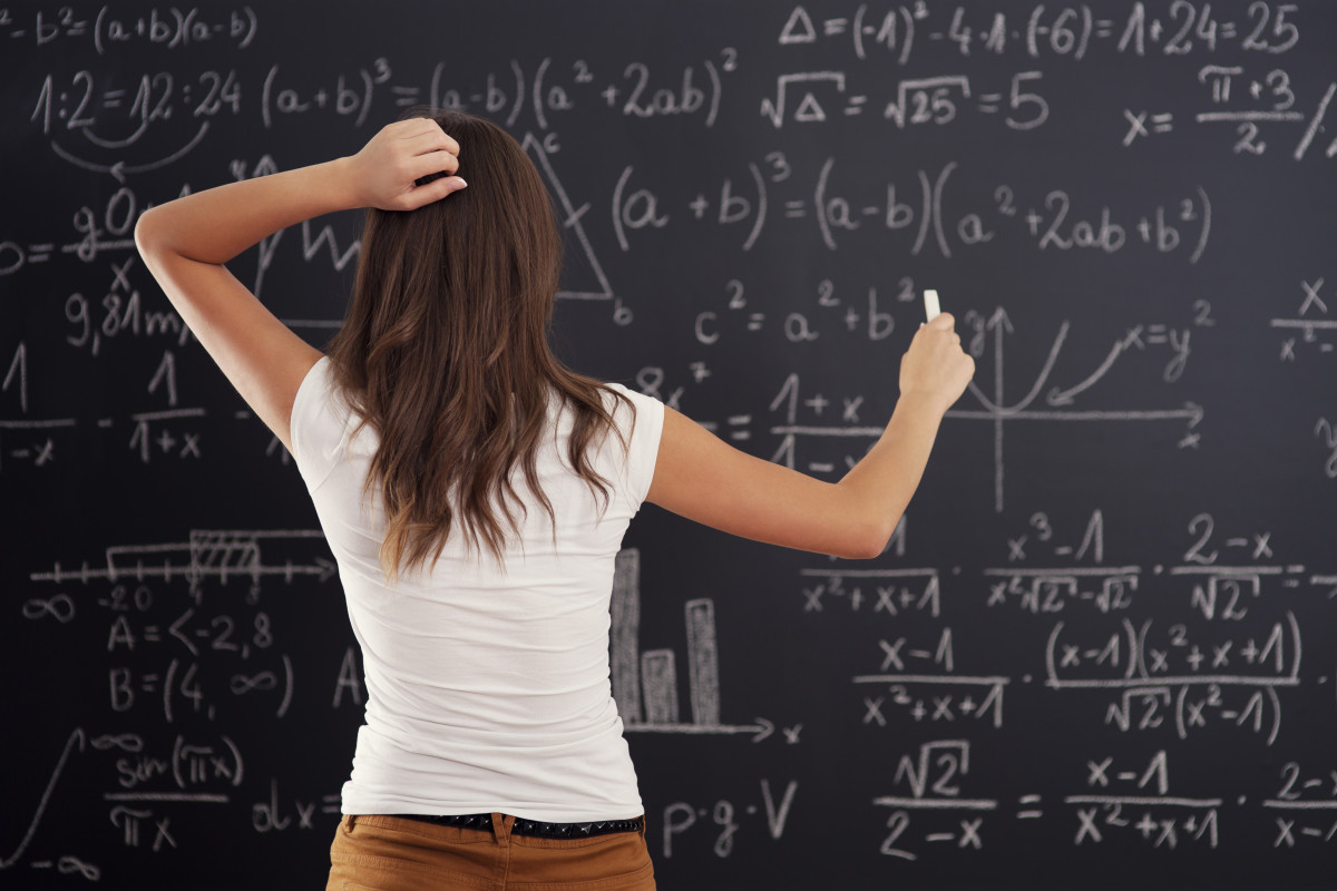 Mujer joven mirando problema de matematicas en la pizarra