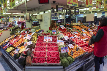 Una mujer espera ante un puesto de fruta del mercado