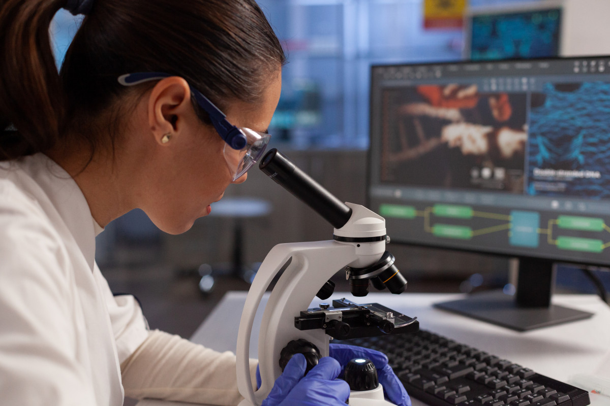 Bioquimico que trabaja en el microscopio para la ilustracion celular en la pantalla de la computadora en el laboratorio quimico mujer cientifica analizando adn del virus tejido celular diagrama de nucleo de plasma y hemoglobina
