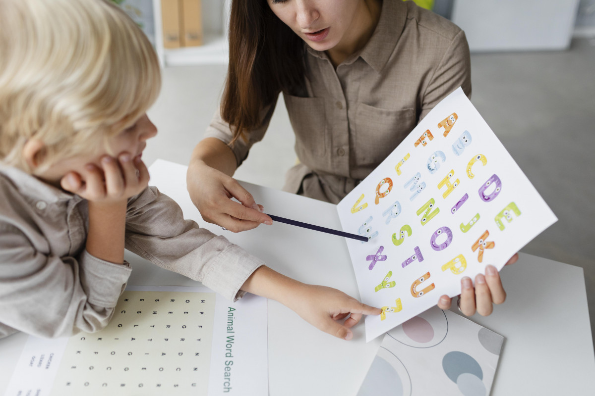 Mujer haciendo logopedia con un nino en su clinica