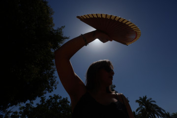 FOTODELDÍA CÓRDOBA (ANDALUCÍA), 04/08/2025.- Una mujer se protege con un abanico del sol este lunes, en Córdoba (Andalucía). La intensa ola de calor sigue este lunes azotando casi toda la peníns