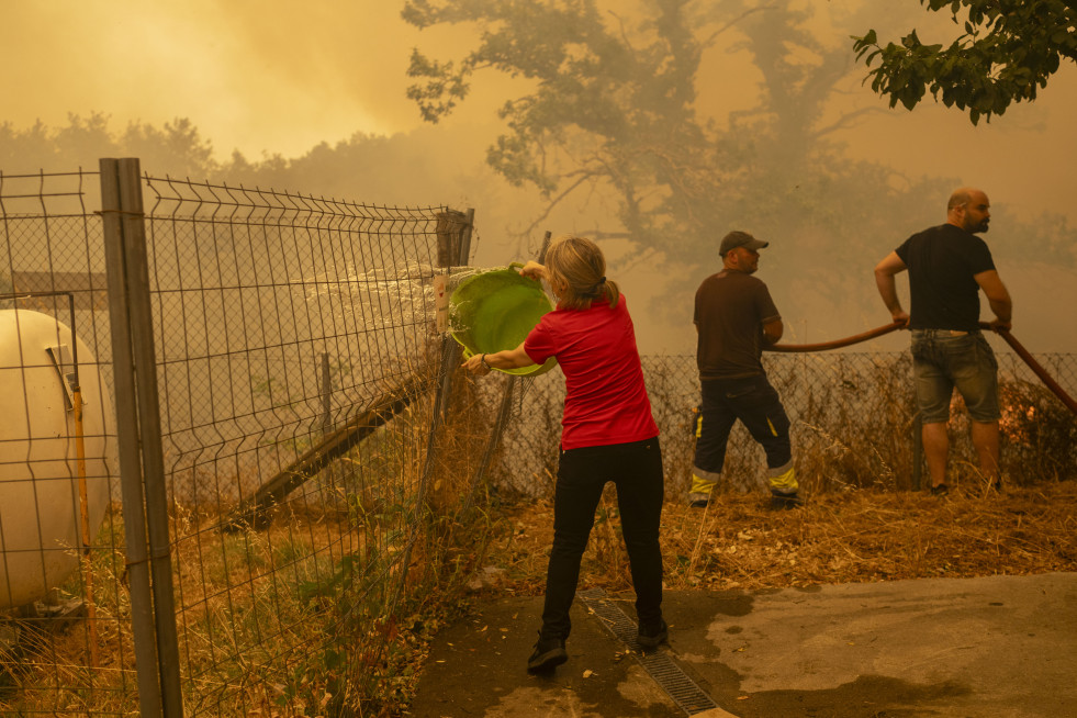 CUALEDRO (OURENSE), 15/08/2025.- Vecinos de la aldea de Lamas (Cualedro) intentan aplacar el fuego que afecta este viernes esta zona de Ourense.La medida de confinamiento por los incendios se ha levan